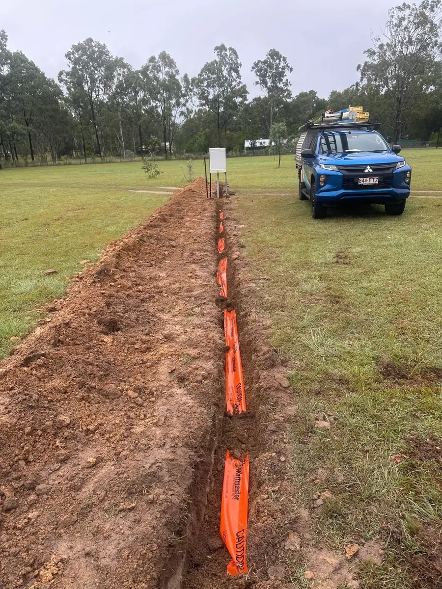 Open trench beside a vehicle on a grassed property